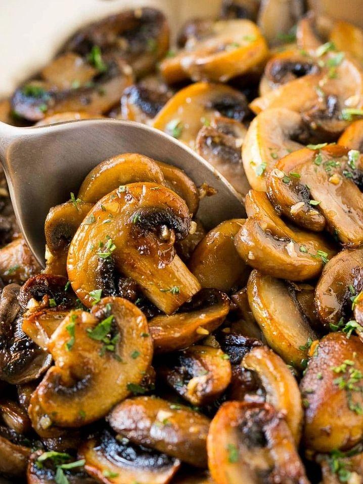 A close-up of sautéed mushrooms being lifted with a spoon