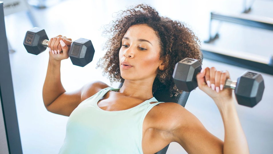 A woman pressing a pair of dumbbells overhead during a strength training session