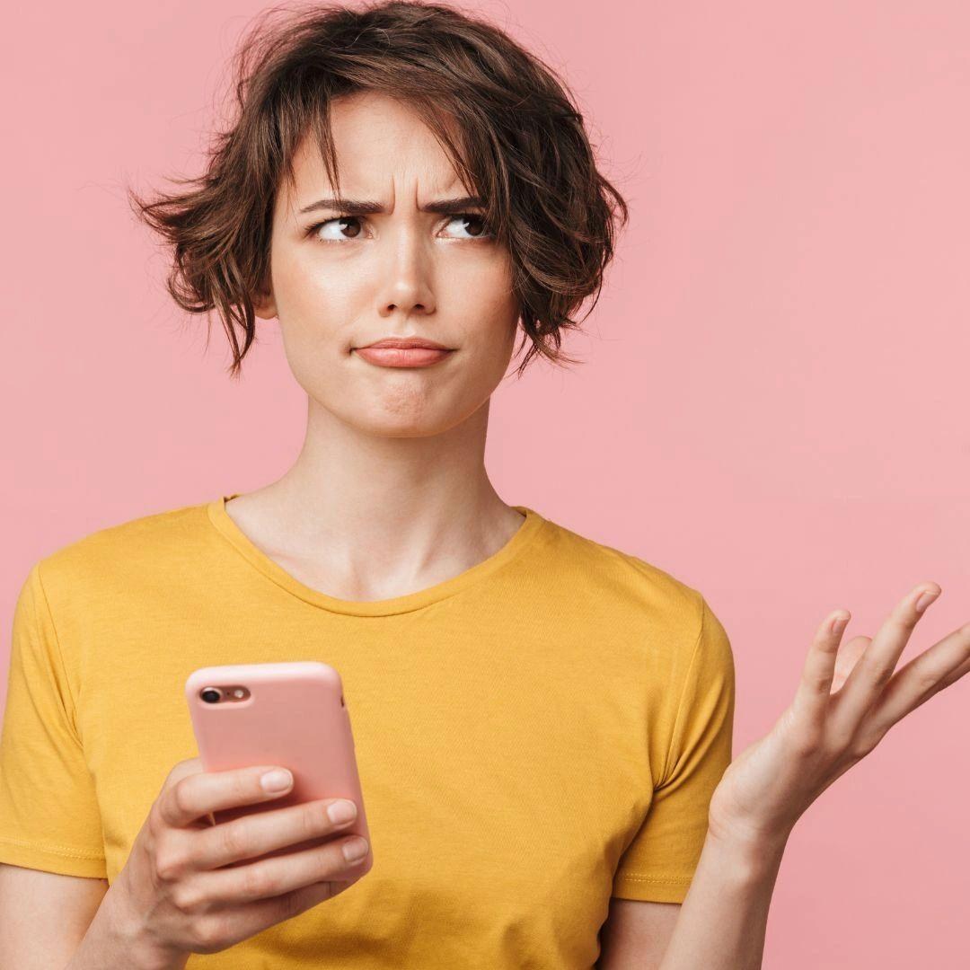 A woman looking confused while holding a smartphone